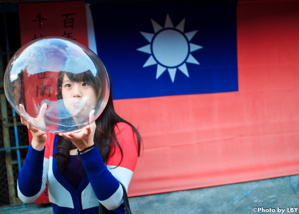 a lady blowing a bubble in front of the Taiwanese flag